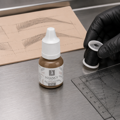 Nuance Pigmento Híbrido Dark Brown 8 ml — frasco fechado num posto de mapeamento de sobrancelhas com fio, régua e pele sintética; SKU NH53958