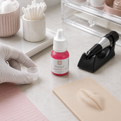 Nuance Pigmento Orgânico Junket 8 ml — frasco fechado num posto de treino labial com taça vazia e pele sintética; SKU NO53030